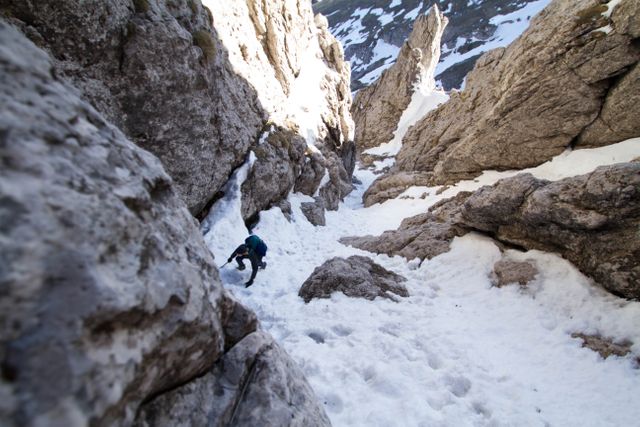 Image of a climber scaling a rugged, snow-covered terrain in a mountainous region. Perfect for promoting adventure tourism, outdoor gear, extreme sports, winter activities, and nature exploration.