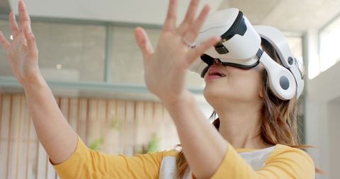 Mid-Adult Woman Wearing White VR Headset Reaching Forward in Bright Minimal Home Interior