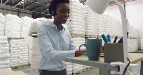 Warehouse Manager Communicating with Headset at Standing Desk