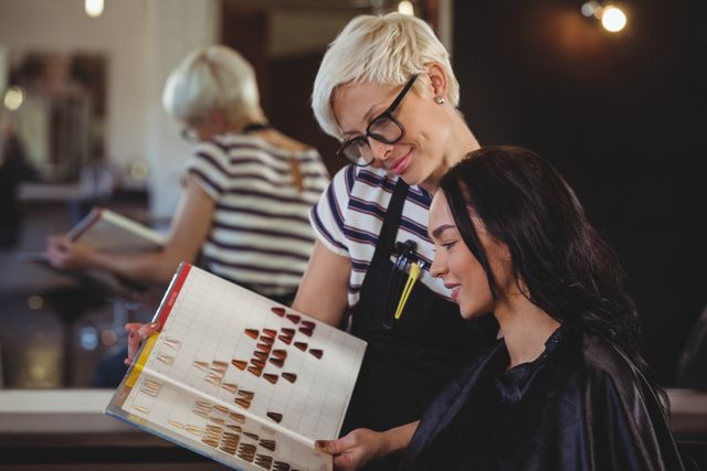 Woman consulting with stylist about hair color options in a salon. Ideal for use in beauty industry promotions, hair care product advertisements, and salon service marketing materials.