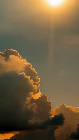 Sun rising above cumulus clouds casting golden glow in vertical timelapse