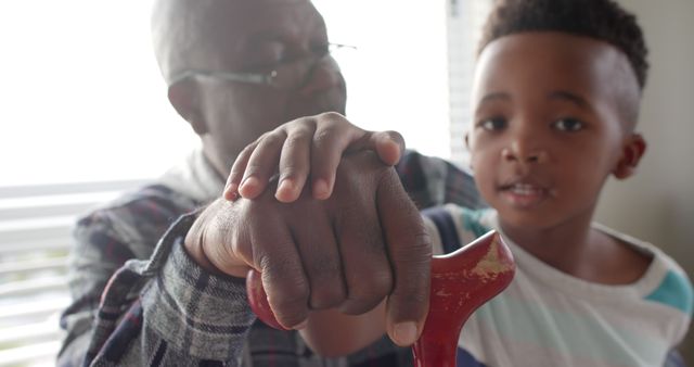 African american grandfather with walking stick and grandson holding hands at home. Lifestyle, childhood, free time, family, togetherness and domestic life, unaltered.