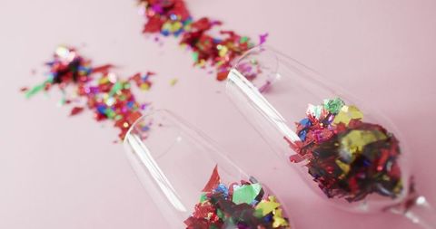 Champagne Glasses Filled With Colorful Confetti on Pink Background