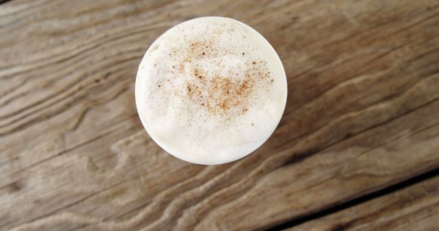 Overhead view of frothy cappuccino with cinnamon on rustic wooden table - Download Free Stock Images Pikwizard.com