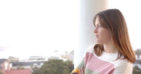 Thoughtful Young Woman Enjoying Serene Balcony Views in Urban Setting