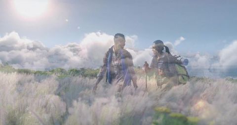 Couple Backpacking Through Sunny Hillside Meadow