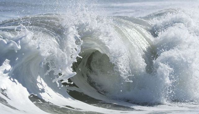 Powerful ocean wave curling into hollow barrel with foamy spray and churning whitewater