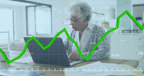 Senior woman engaging with financial data graphs on laptop
