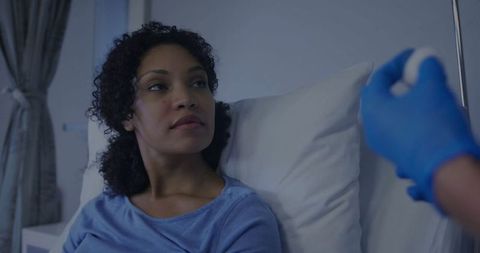 Female patient observing nurse with syringe in hospital room