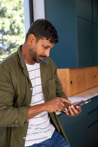 Man Using Smartphone in Modern Kitchen with Natural Light