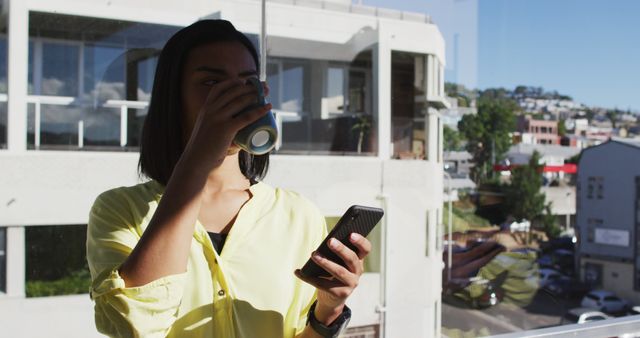 Businesswoman Drinking Coffee and Using Smartphone by Office Window - Download Free Stock Images Pikwizard.com