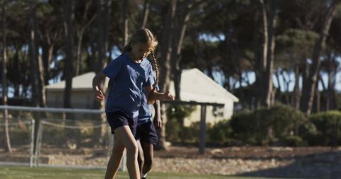 Diverse teenage teammates controlling soccer ball during outdoor practice on grassy field
