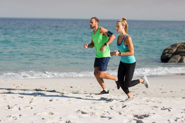Full length of young couple jogging at beach
