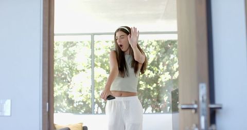 Teenage Girl Dancing with Headphones and Smartphone in Bright Room