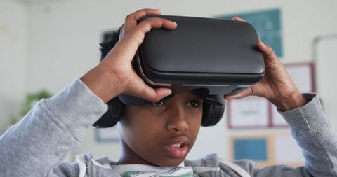 African male student exploring virtual reality with vr headset and headphones in classroom