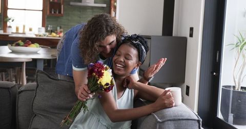 Romantic surprise at home: young man gifts flowers to smiling partner