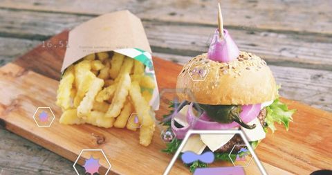 Seeded burger and crinkle fries sitting on rustic wooden board with digital overlays