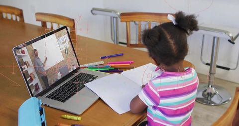 Young girl learning drawing online at home with laptop, colorful markers and notebook