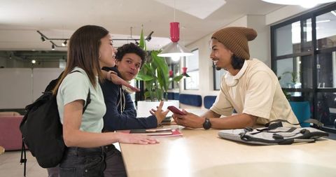 Young african american friends collaborating around wooden communal table in coworking lounge