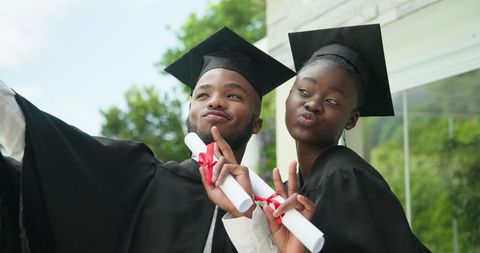 Joyful Graduates Celebrating Milestone in Cap and Gown Outdoors