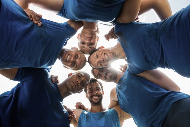 Group of fit individuals huddling together in a bootcamp, showcasing unity and teamwork. Ideal for promoting fitness programs, team-building activities, and motivational content. Perfect for use in advertisements, social media posts, and fitness blogs.