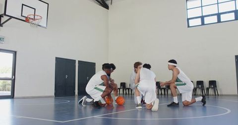 Diverse Male Basketball Team Huddling for Strategy on Court