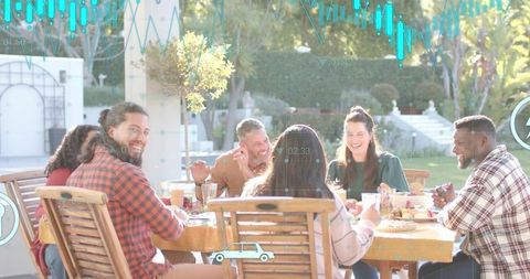 Friends laughing sharing meal around backyard table during sunny outdoor gathering