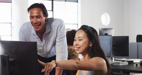 Diverse colleagues collaborate on computer project in office