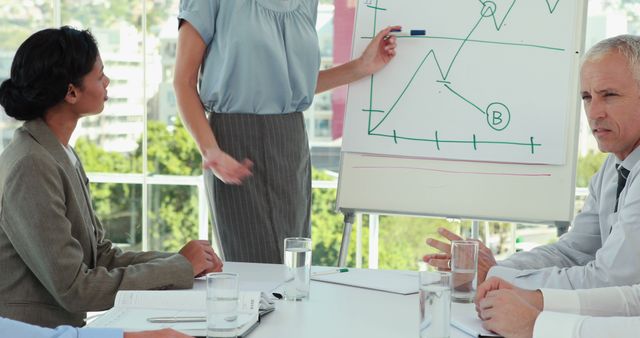 Business professionals discussing a financial chart during a meeting, highlighting teamwork and collaboration in a modern office environment. Ideal for usage in business blogs, financial consulting websites, presentations, and educational materials showcasing workplace dynamics and teamwork.