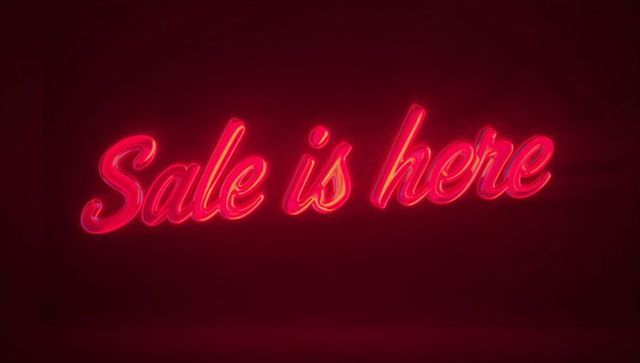 Glowing red neon script sign 'sale is here' casting halo for retail promotion and ads