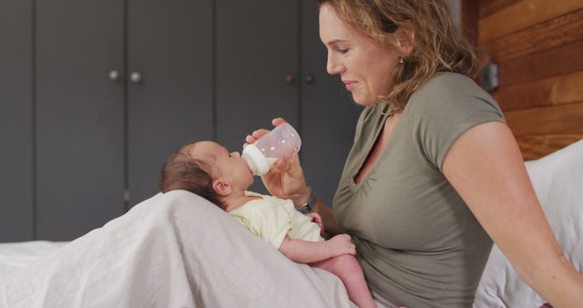 Mother bottle feeding baby in cozy bedroom, conveying a nurturing and intimate family moment. Useful for parenting blogs, family health articles, baby care products, and motherhood-related advertisements.