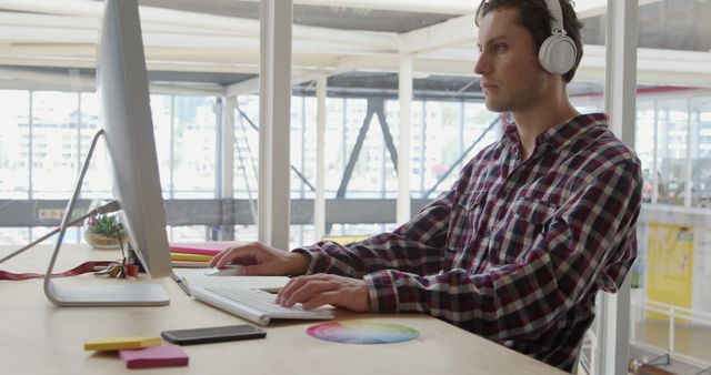 Focused Male Designer Working at Computer with Headphones in Bright Office - Download Free Stock Images Pikwizard.com