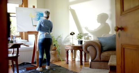 Senior Woman Painting in Sunlit Room at Home in Serenity