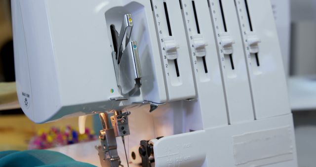 Closeup view of serger sewing machine in tailoring studio, used for stitching fabrics and creating professional seams. Home sewing projects or industrial textile manufacturing visuals would benefit. Ideal for illustrating modern tailoring tools and craftsmanship.