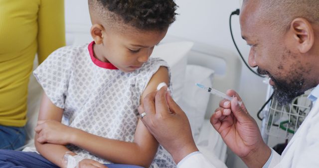 African american male doctor vaccinating child patient at hospital. Medicine, healthcare, lifestyle and hospital concept.