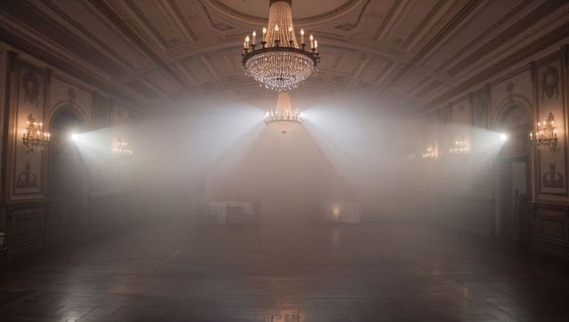 Crystal Chandelier Casting Dramatic Light Beams Across Hazy Ornate Ballroom Interior