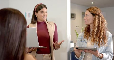 Diverse Professional Women Collaborating with Technology in Office