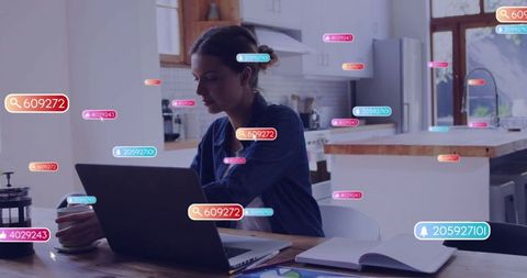 Woman working remotely at kitchen table with data tags floating