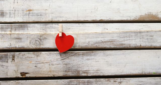 A red heart is clipped to a white wooden background, with copy space. It symbolizes love and could be used for themes like Valentine's Day or romantic occasions.