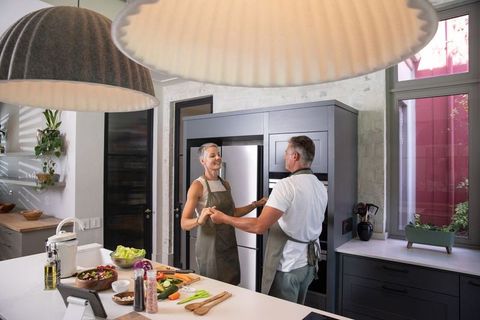 Happy Senior Couple Dancing in Modern Kitchen While Preparing Meals