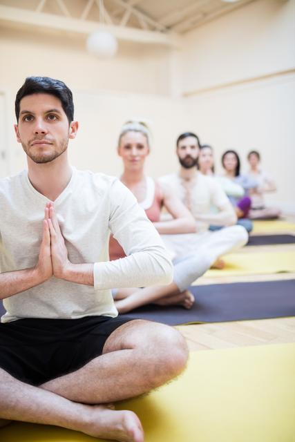 People sitting in lotus position, practicing meditation in a fitness studio. Ideal for illustrating mindfulness, group fitness activities, yoga practice, and healthy living. Suitable for wellness blogs, fitness websites, meditation guides, and lifestyle publications.