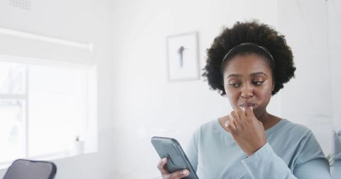 Woman Multitasking Brushing Teeth with Smartphone in Bathroom