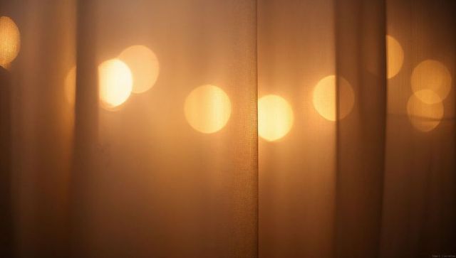 Sheer curtain panel with warm bokeh lights filtering through window for cozy ambience