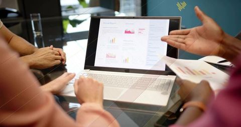 Team reviewing annual report on laptop during collaborative office meeting
