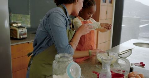 Mother and Daughter Cooking Together Cracking Eggs in Kitchen