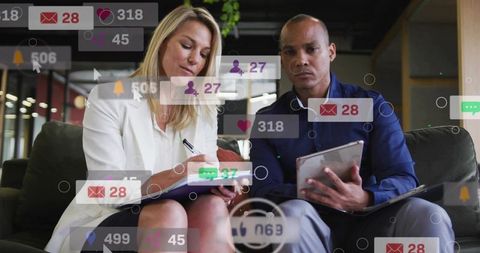 Business colleagues collaborating with tablet and notebook amid social media notification overlays