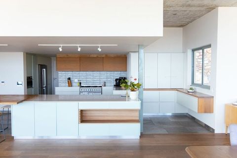 Modern minimalist kitchen featuring central island, wood accents and stainless appliances