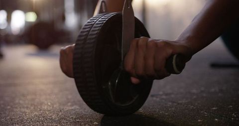 Close-up of hands using ab wheel in gym for core workout
