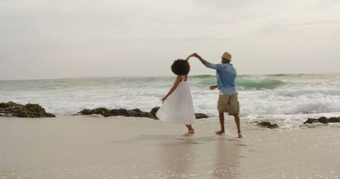 Couple Dancing Joyfully on Sandy Beach Under Blue Sky - Download Free Stock Images Pikwizard.com
