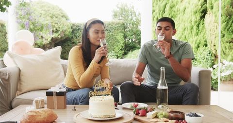 Couple Celebrating Anniversary with Cake and Drinks in Garden Patio